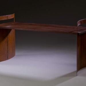 A sculptural bench with curved oxidized steel legs supporting a solid walnut plank, combining industrial metal and warm wood.